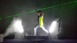 A man in neon jacket and jeans on stage.