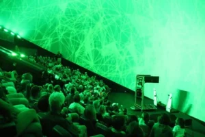 A crowd of people in an auditorium with green lighting.