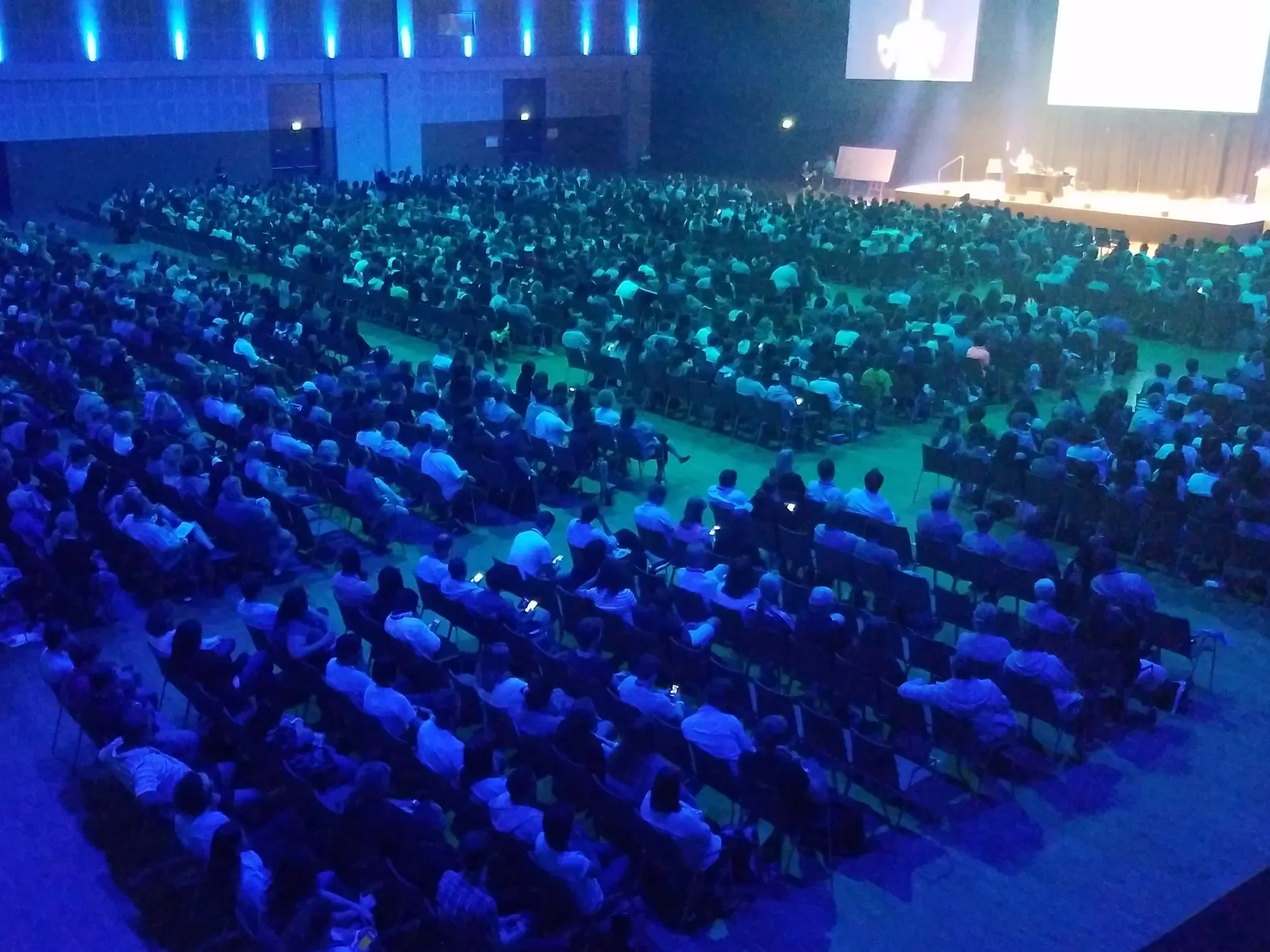 A large crowd of people sitting in the middle of an auditorium.